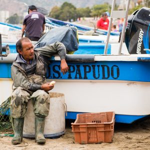 Pescador sentado al lado de su barco