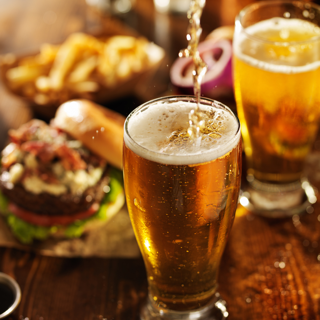 fotografía cervezas servida en mesa con comida y picoteo