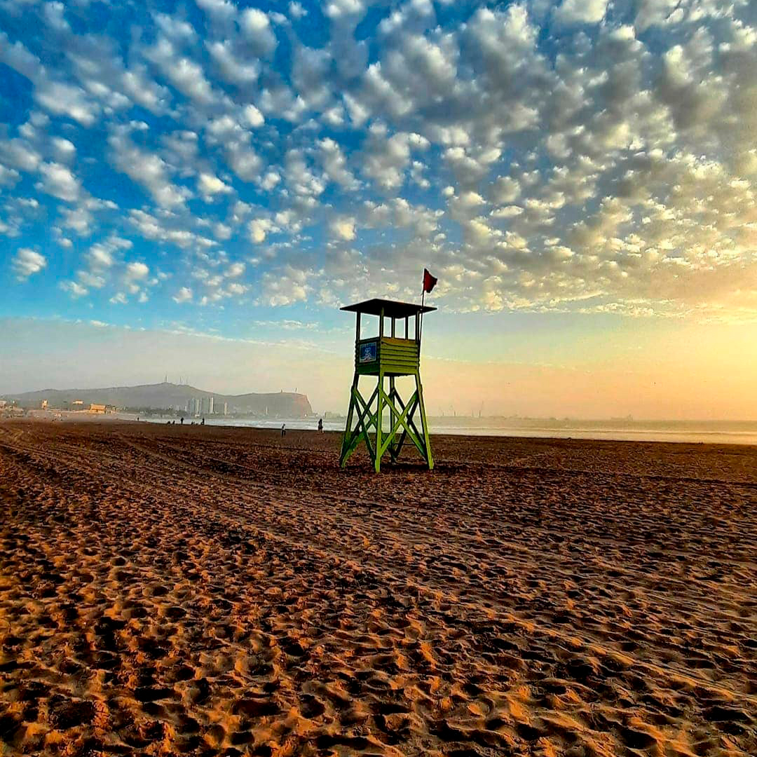 fotografía de playa en atardecer y torre de salvavidas