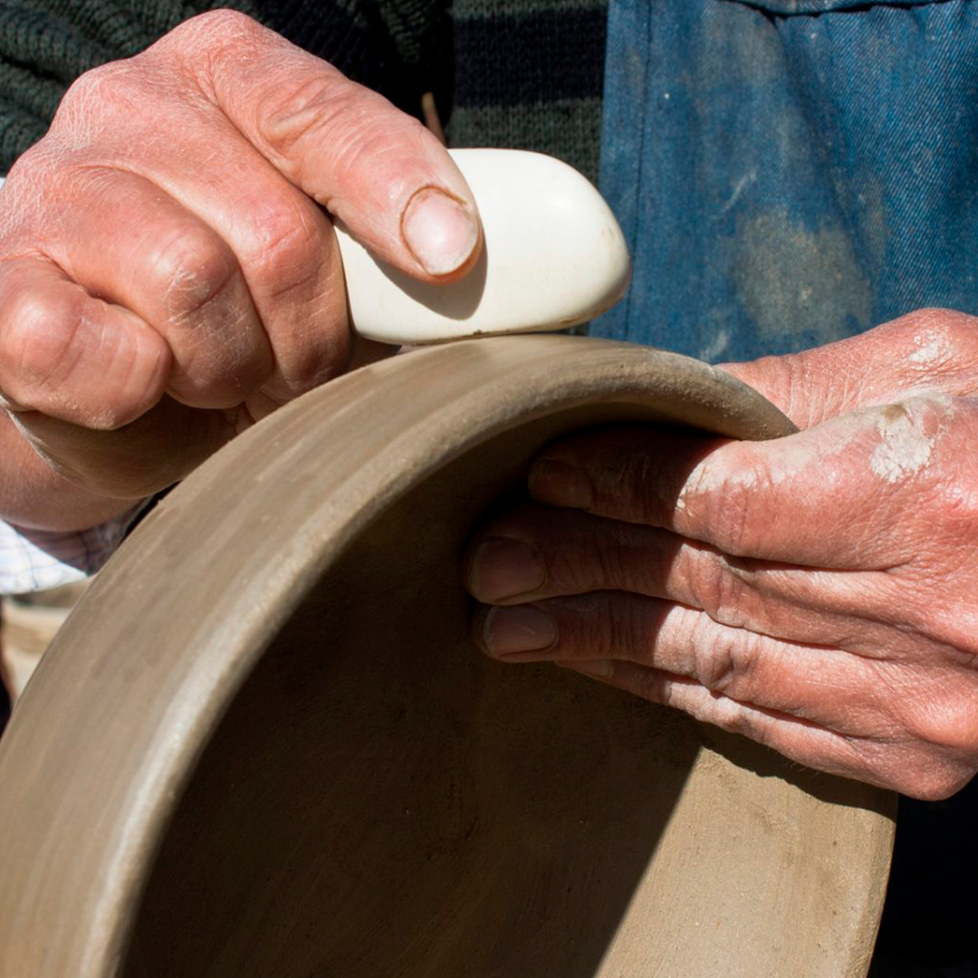Manos de un hombre trabajando artesanías en arcilla de Pañul.