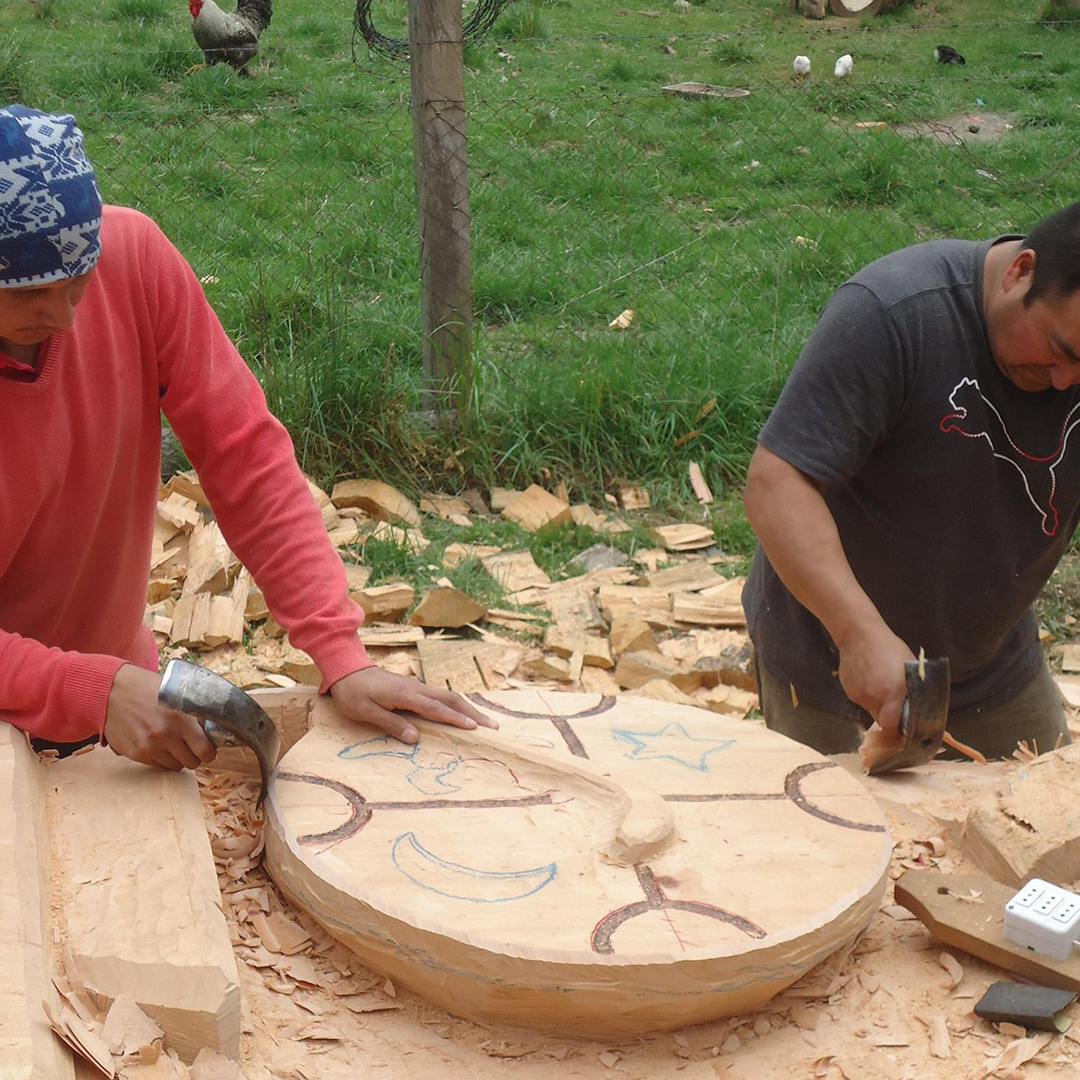 Hombres artesanos trabajando en madera de raulí.