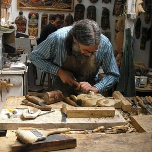 Hombre tallando máscaras en madera que representan la cultura changa.