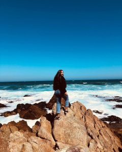 mujer en las rocas contemplando el mar