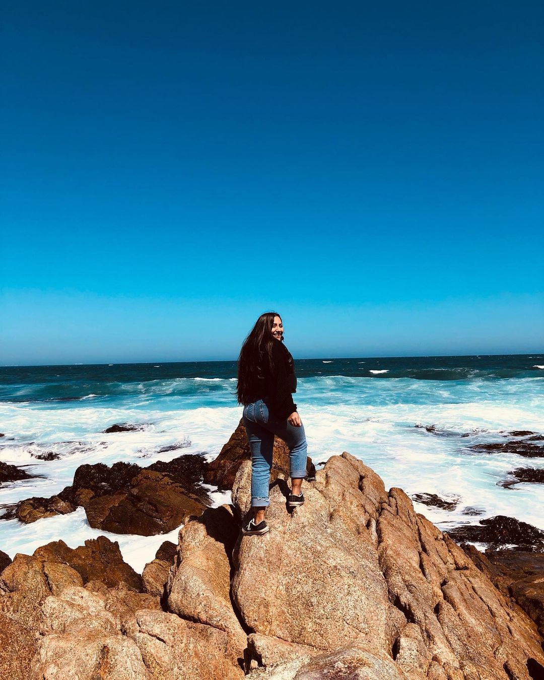 mujer en las rocas contemplando el mar