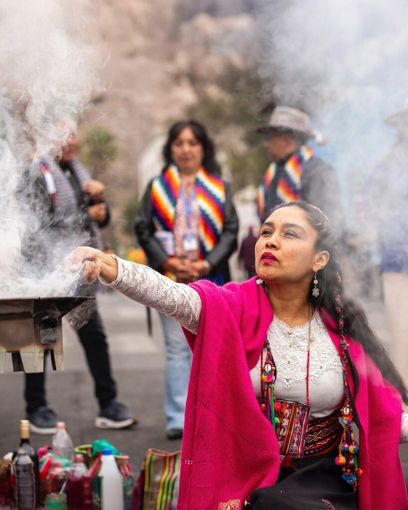 Una mujer aymara con una manta rosa realiza una ofrenda Phawa con humo ceremonial, durante la celebración del Machaq Mara en la Región de Arica y Parinacota.