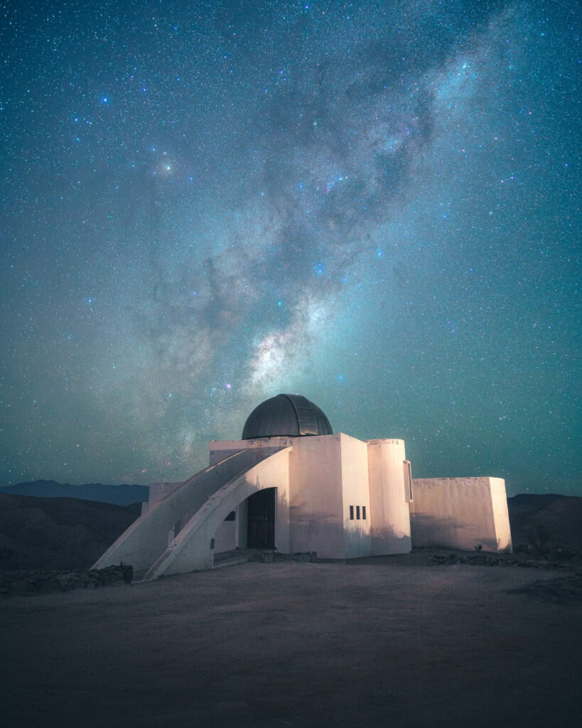 El moderno edificio blanco del Observatorio Collowara iluminado tenuemente bajo un espectacular cielo estrellado con la Vía Láctea, un punto clave para el astroturismo en la Región de Coquimbo.