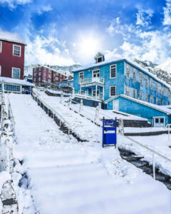 Vista de las coloridas edificaciones de madera azul y roja en el campamento minero de Sewell cubierto por una capa gruesa de nieve invernal, con sus clásicas escaleras centrales nevadas.