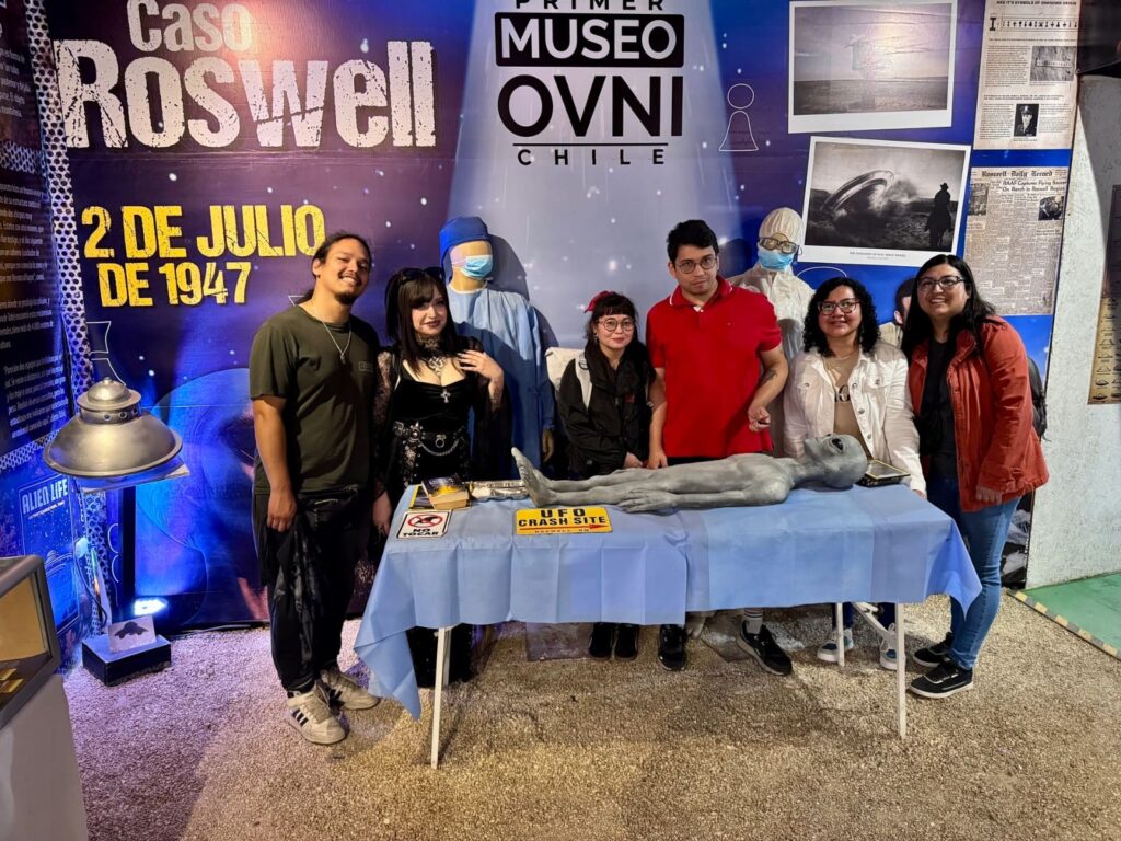 Grupo de visitantes posando junto a una réplica de extraterrestre sobre una camilla, recreando el caso Roswell de 1947, en una de las salas temáticas del Museo OVNI en La Serena.