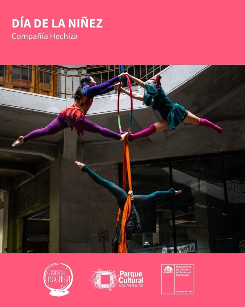 Afiche de "Día del Niño" con dos artistas de circo aéreo realizando acrobacias con telas y un aro en el aire, junto a los logos de la Compañía Hechiza y el Parque Cultural de Valparaíso.