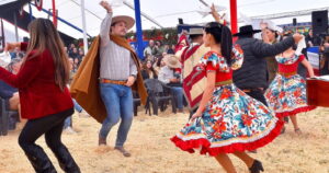Parejas bailando cueca con trajes típicos y pañuelos al viento durante una fonda, en una de las celebraciones de Fiestas Patrias 2026 que se vivirán de norte a sur del país.