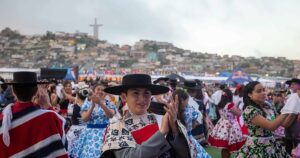 Jóvenes bailando cueca al aire libre con la Cruz del Milenio de fondo, en una de las fondas y ramadas en Coquimbo durante Fiestas Patrias.