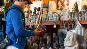 Visitante observando tallados de moái en un puesto de artesanía, una de las paradas del Circuito Hanga Roa.