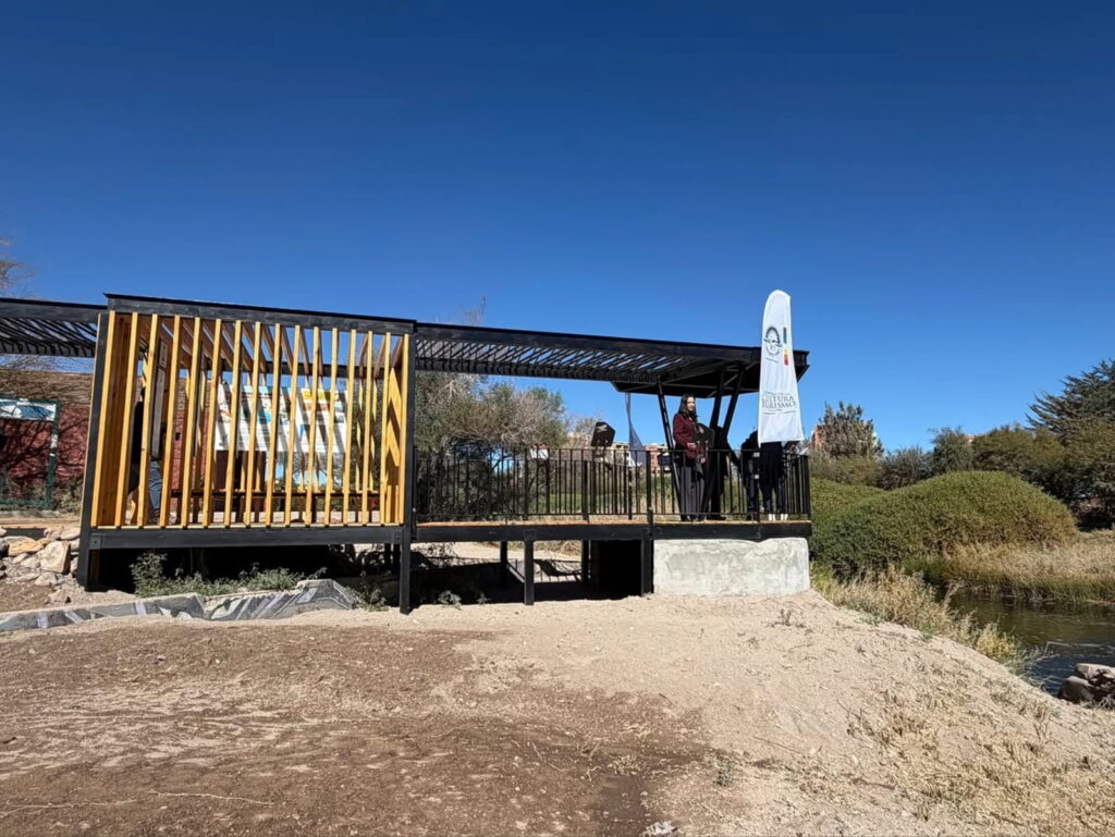 Mirador de madera y estructura metálica junto al río Loa en el Parque El Loa, en Calama, con vegetación nativa y aguas tranquilas de fondo, uno de los destinos para escapadas de fin de semana sin auto en el desierto.