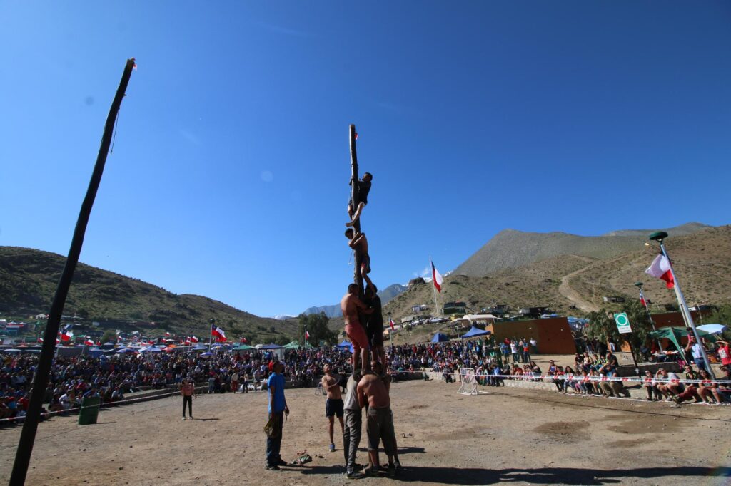 Personas jugando palo encebado en la Pampilla de San Isidro de Vicuña.