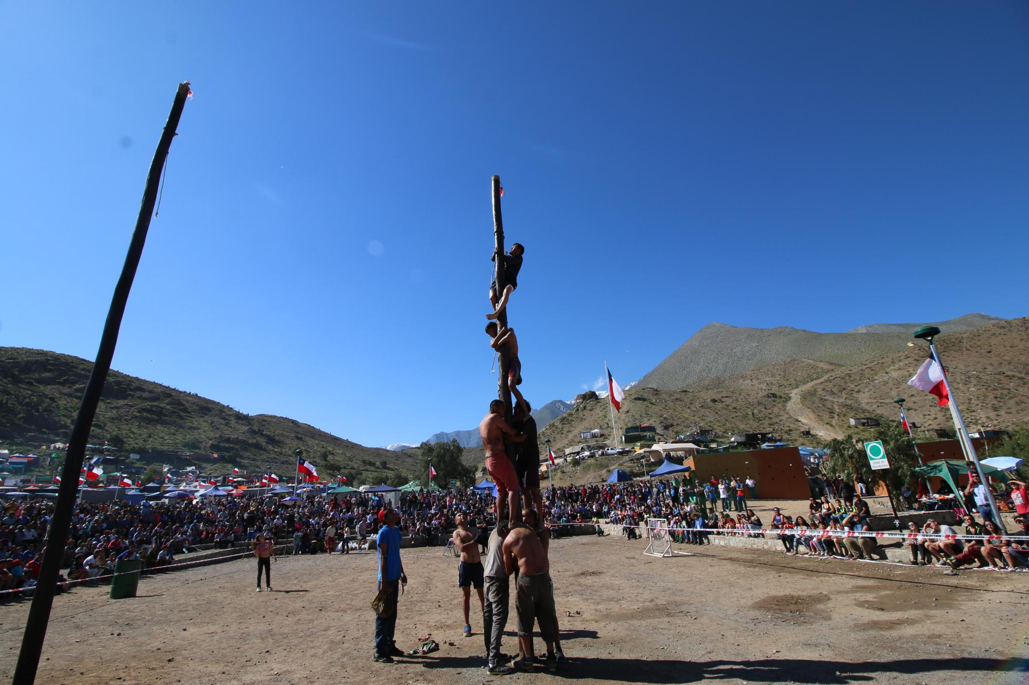 Personas jugando palo encebado en la Pampilla de San Isidro de Vicuña.